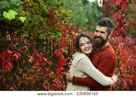 Couple With Smiling Faces Cuddle Each Other With Tenderness. Couple In Love Hugs With Red Leaves On 