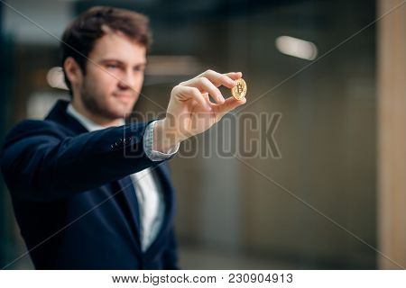 Golden Bitcoin In Hand With Businessman Blurred On Background, Digitall Symbol Of New Virtual Curren