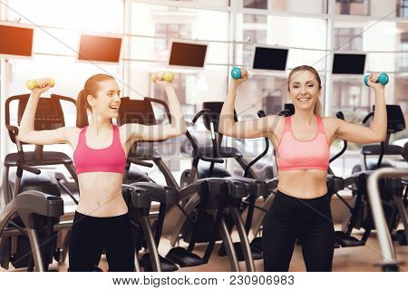 Mother And Daughter In Sportswear Doing Exercises With Dumbbells At The Gym. They Look Happy, Fashio