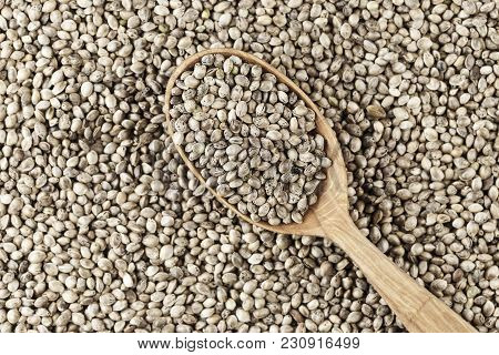 Hemp Seeds Are Scattered As A Background, On Top Lies A Rustic Wooden Spoon