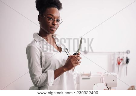 Smiling African Seamstress Looking At Camera With Sewing Machine
