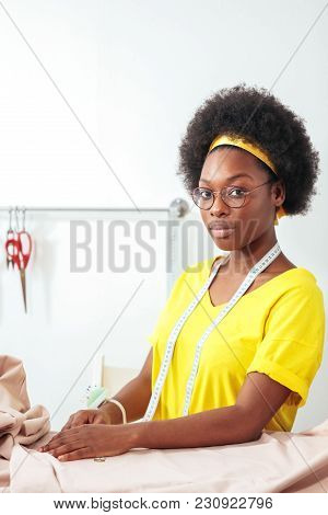 Smiling African Seamstress Looking At Camera With Sewing Machine