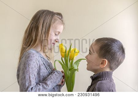 The Little Gentleman Gives The Girl A Bunch Of Flowers. The Little Boy Gives A Bouquet Of Yellow Tul