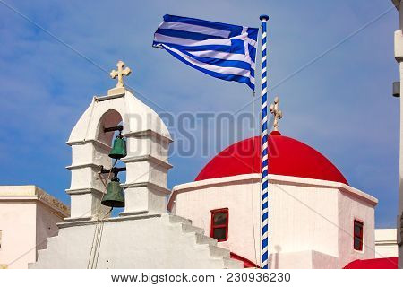Agia Kyriaki Church, Typical Greek Church White Building With Red Dome And Large Waving Greek Flag A