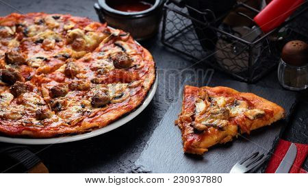 Homemade Pizza With Chorizo, Mushrooms, Mozzarella And Pieces Of Chipolata Sausages On Dark Table.