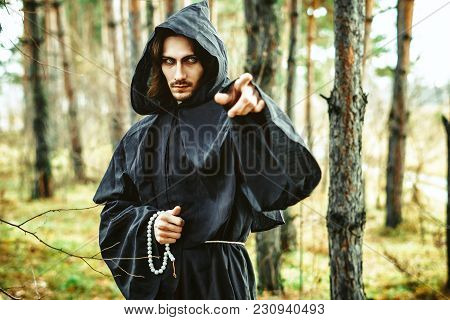 The Black Monk Pointing His Finger In The Woods