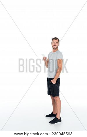 Smiling Man In Sportswear And Earphones Listening Music Isolated On White