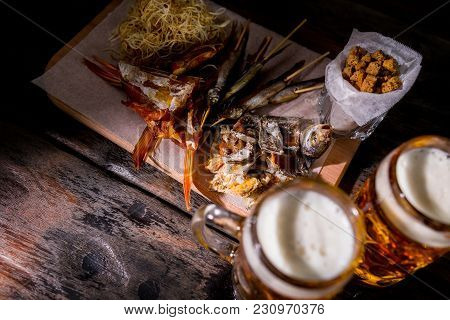 Assorted Beer Snacks With Cheese Chechil, Dried Fish And Crackers, Served On The Rustic Cutting Boar