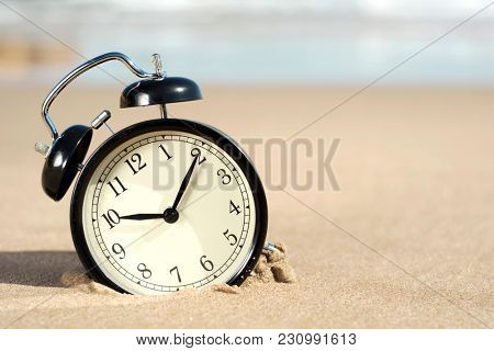 closeup of an alarm on the sand of the beach, next to the seashore, with some blank space on the right