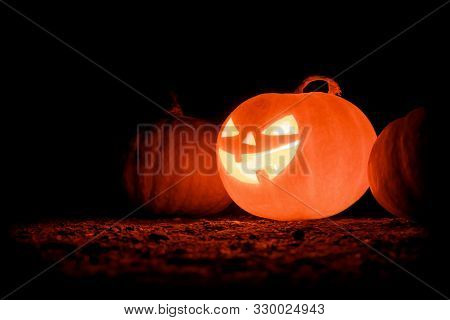 Glowing Halloween Pumpkin On A Black Background. Creepy Pumpkin. Copyspace.