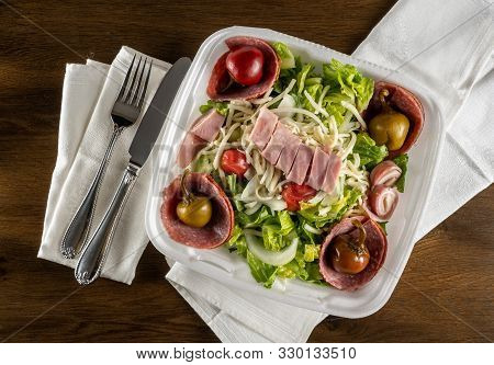 Flat Lay View Of Antipasta Salad With Ham, Salami Peppers And Lettuce In A Delivery Plastic Box And 