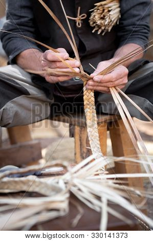 Old Wicker Craftsman With Hands Working In Isolated Foreground.