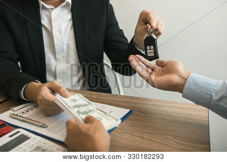 New Car Buyers And Car Sales Agent People Are Exchanging By Giving Cash And New Car Keys To Each Oth