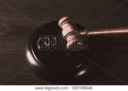 Brown Judje Wooden Gavel And Wedding Rings On The Table. Divorce Process Concept.