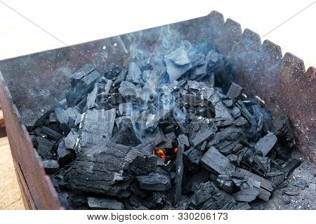 Black Charcoal On The Grill With Light Smoke.