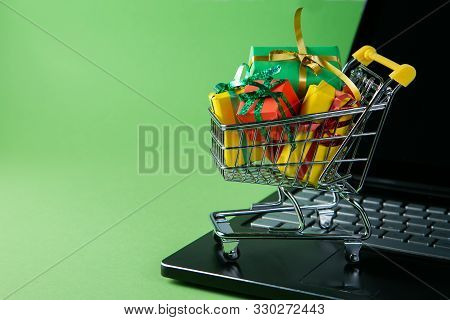 Ciber Monday Concept - Trolley Cart With Christmas Presents On Notebook, Green Background