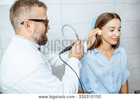 Senior Otolaryngologist Making Endoscopic Examination Of An Ear For A Young Patient At The Ent Offic