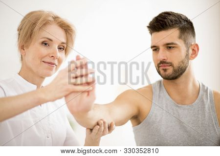 Handsome Young Man During Physiotherapy Session With Professional Doctor