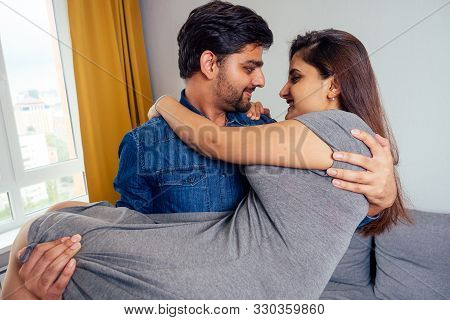 Happy Indian Couple Dancing Together In New Light Apartment With Design Repair:gray Sofa, Yellow Cur