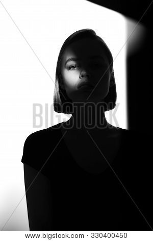 Fashionable Beauty Portrait. Black Silhouette On White Background. Girl With A Spot Of Light On Her 