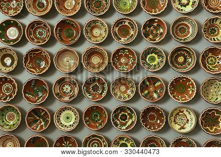 Opishnya, Ukraine - July 4, 2019: Group Of Clay Bowls With Patterns Hanging On A Wall At The Nationa