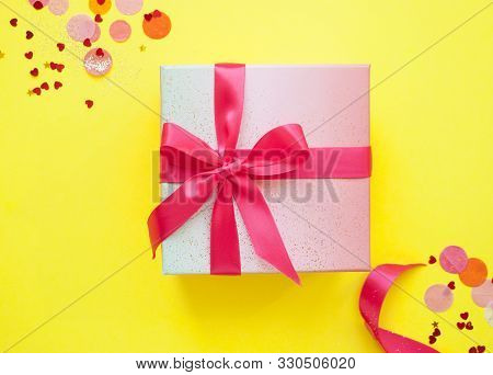 Giftbox Tied With Pink Color Ribbon On Bright Yellow Background With Sparklets And Confetti. Flat La