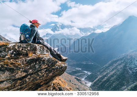 Young Hiker Backpacker Female Sitting On Cliff Edge And Enjoying The Imja Khola Valley During High A