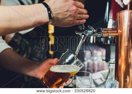 Close Up Of A Male Bartender Dispensing Draught Beer In A Pub Holding Large Glass Tankard Under A Sp