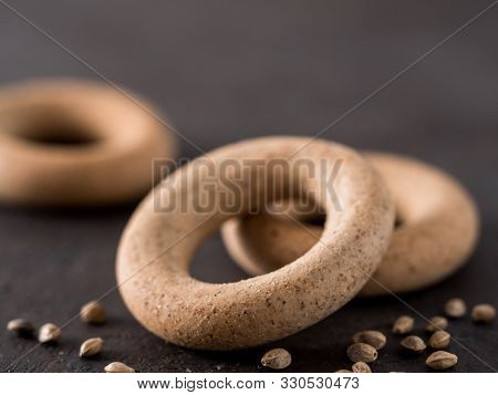 Ring-shaped Cracknel With Whole Grain Hemp Seed Flour And Hemp Seeds On Black Background. Ring-shape