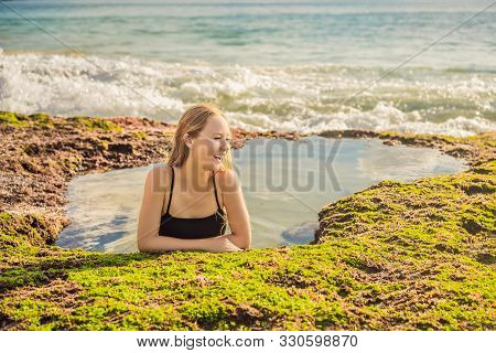 Young Woman Tourist On Pantai Tegal Wangi Beach Sitting In A Bath Of Sea Water, Bali Island, Indones