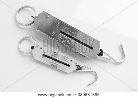 Two Silver Steelyards Of 10 Kg And 25 Kg On A Light Background. Kitchen Utensils. Weighing Tool.