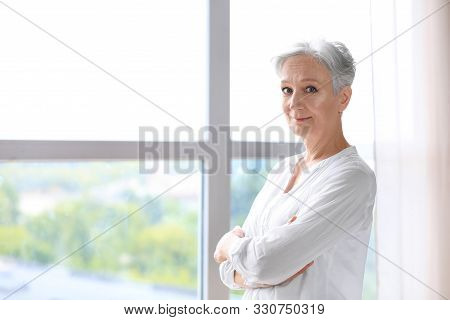 Happy Mature Woman Near Window Indoors, Space For Text. Smart Aging