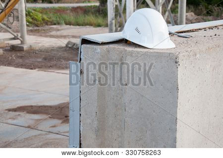 White Construction Hat On A Concrete Slab. Headpiece For Protection. Protecting A Person At A Constr