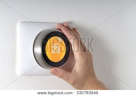 Smart Thermostat With A Hand Setting Up The Temperature