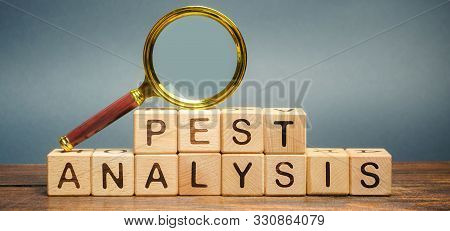 Wooden Blocks With The Word Pest Analysis And A Magnifying Glass. Political, Economic, Socio-cultura