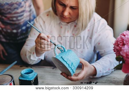 Woman Working In Her Pottery Studio. Ceramic Workshop. Paint On Clay Cup In The Pottery. Painting In