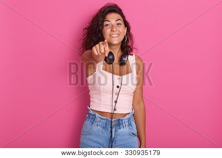 Close Up Portrait Of Pretty Girl Isolated Over Pink Studio Background, Poiting With Her Index Finger