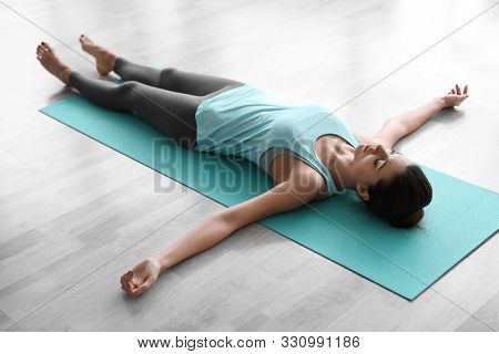 Young Woman Practicing Corpse Asana In Yoga Studio. Savasana Pose