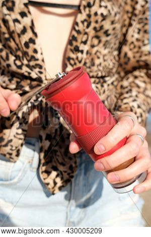 Red Manual Coffee Grinder In Female Hands Close Up. On Nature, Sea Background. Barista Girl