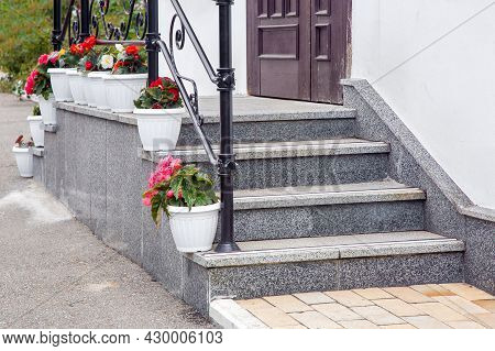Steps Leading Up To A Threshold Building Of Granite Stairs With Railing And Plastic Pot With Floers 