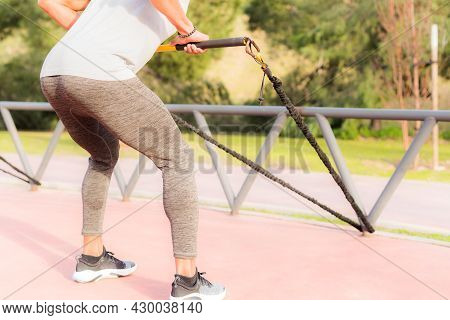 Back View Of An Atlhetic Sportsman Exercising With A Fitness Strap.