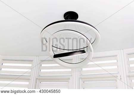 Modern Round White Chandelier With Led Lamps Hanging On The Ceiling In The Apartment