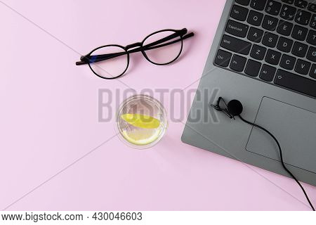 Podcast Recording, Education Concept. Laptop, Microphone, Glasses And Water On A Pink Background.