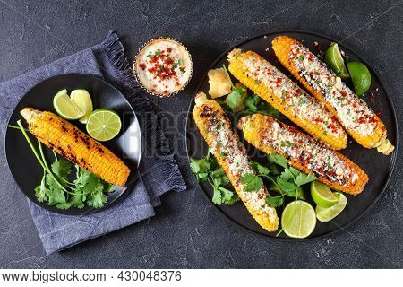 Elote On A Black Plate, Grilled Mexican Street Corn, Charred Cobs Are Slathered In Sour Cream Based 