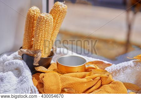 Corns, Autumn Leaves, Pine Cones And Coffee Cup On Windowsill. Creative Autumnal Background Near The