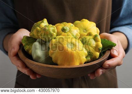 Woman With Wooden Bowl Of Fresh Ripe Pattypan Squashes On Grey Background, Closeup