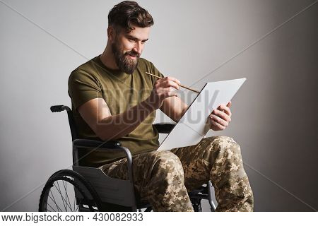 Military Man Sitting In A Wheelchair And Painting A Picture With A Brush