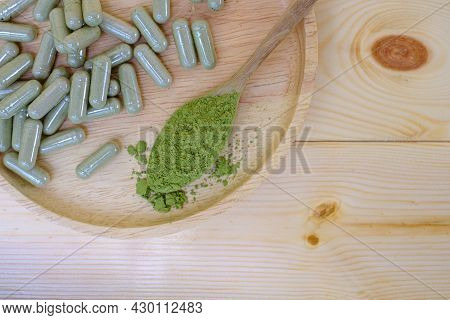 Kariyat Or Andrographis Paniculata Powder In Wooden Spoon With Herbal Capsules On Wood Dish
