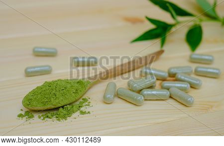 Kariyat Or Andrographis Paniculata Powder In Wooden Spoon With Herbal Capsules And Banch Green Leave