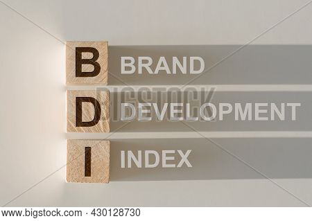 Wooden Cubes With The Word Bdi - Brand Development Index, With A Falling Shadow On A Gray Background